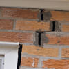 A brick wall displaying stair-step cracks and messy tuckpointing on a Dublin home