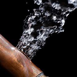 A bursting copper pipe in Dublin, with water gushing out.