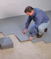 Contractors installing basement subfloor tiles and matting on a concrete basement floor in Marysville, Ohio