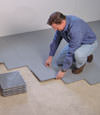 Contractors installing basement subfloor tiles and matting on a concrete basement floor in Dublin, Ohio
