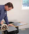 installing a waterproof vapor barrier on a basement floor to prepare for basement carpeting in a Delaware home